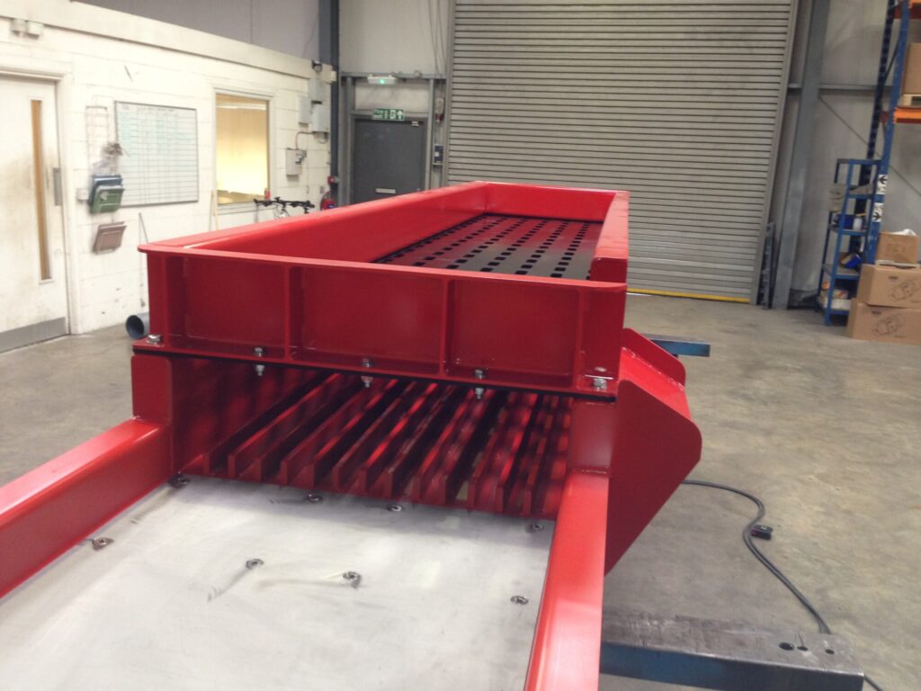 A heavy‑duty vibrating machine used in foundries to break apart sand molds and shake sand from metal castings using strong vertical or linear vibrations.