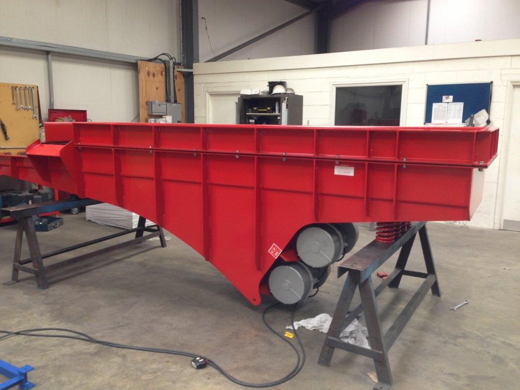 A heavy‑duty vibrating machine used in foundries to break apart sand molds and shake sand from metal castings using strong vertical or linear vibrations. data-large-image=