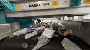 Crossbelt overband magnet operating above a conveyor, removing ferrous metals at a mixed dry recycling plant.