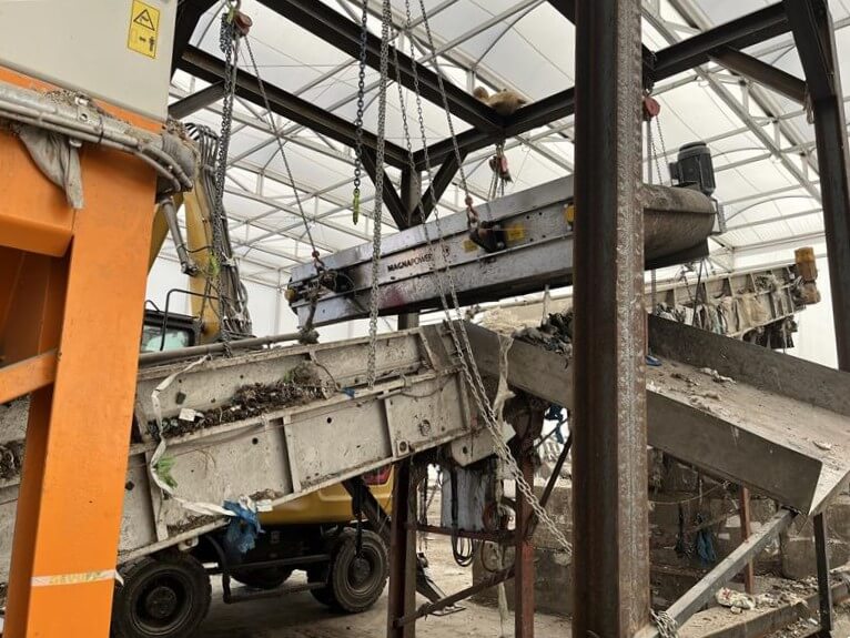 Overband magnet mounted above a conveyor at AEB Amsterdam, extracting metal nitrous oxide canisters from the waste stream. data-large-image=