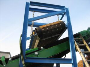 A crossbelt overband magnetic separator with an armoured belt suspended above a conveyor, designed for magnetic separation applications.