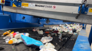 Magnetic overband separator suspended above a conveyor, extracting ferrous metals from the material stream.